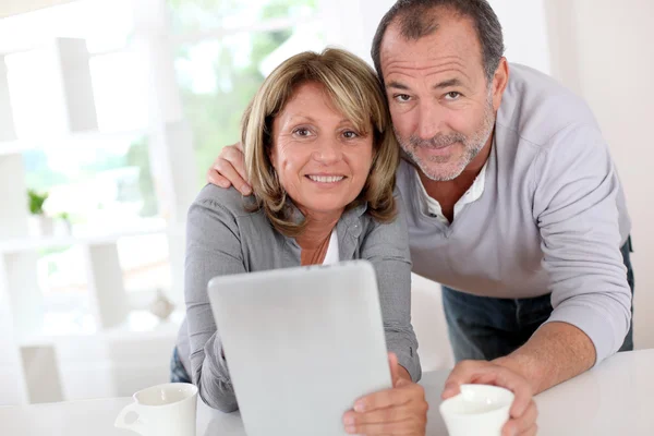 Senior couple drinking coffee in front of tablet Royalty Free Stock Images