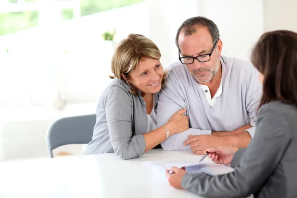 Senior koppel ondertekening financiële overeenkomst Rechtenvrije Stockfoto's