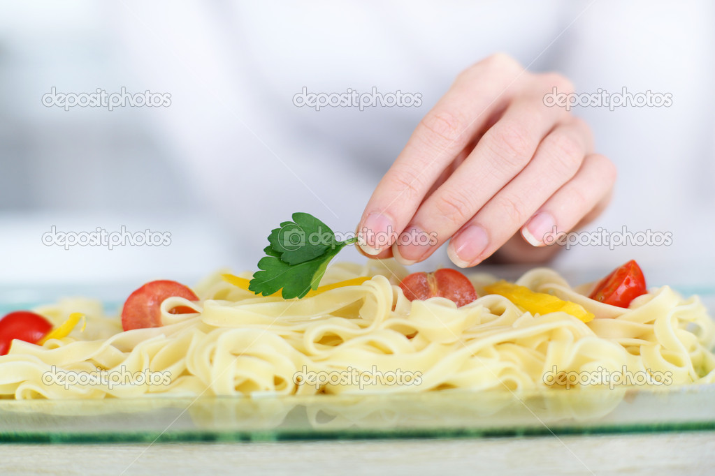 Closeup on woman putting parsley on pasta dish
