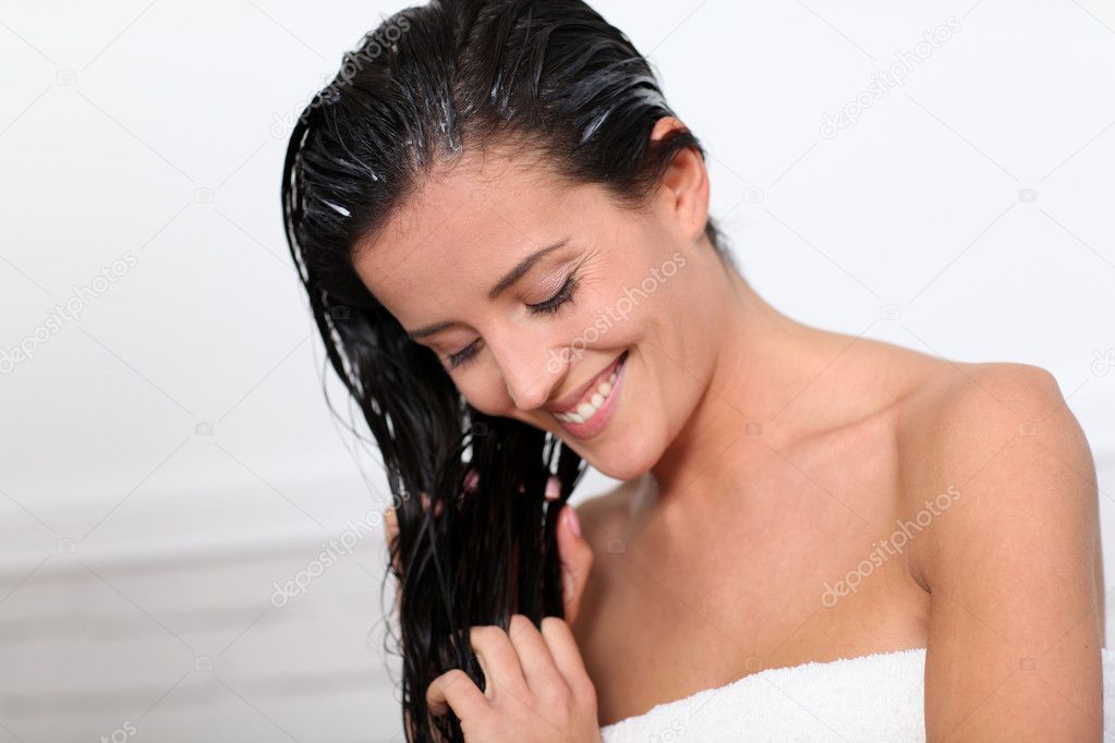 Beautiful woman applying hair conditioner