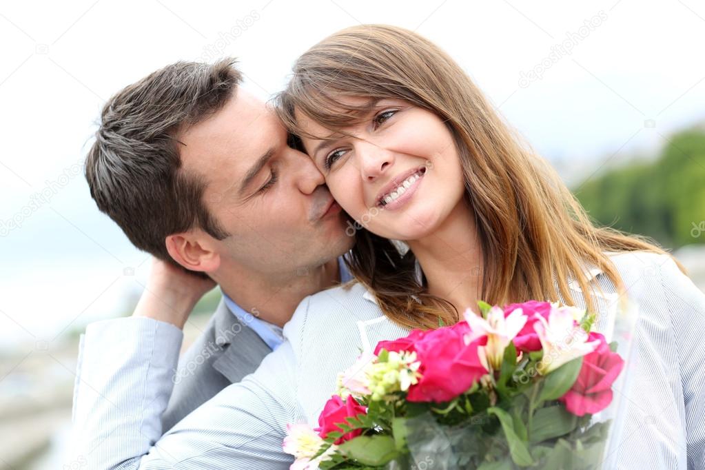 Portrait of romantic man giving flowers to woman Stock Photo by