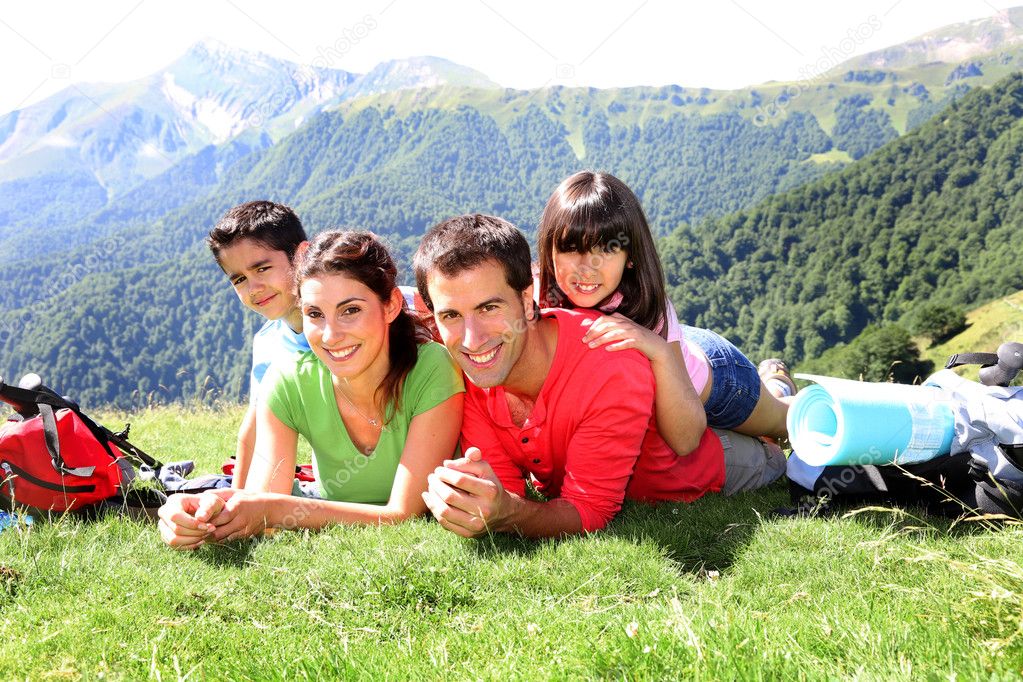 Portrait of happy family laying on the grass in mountain