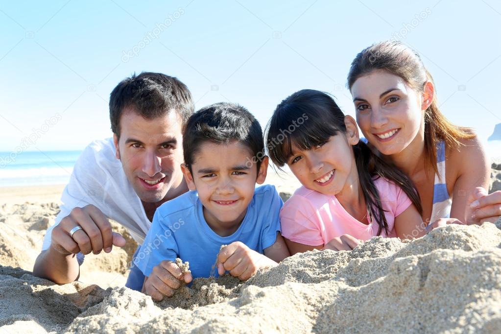 Family of four laying on a sandy beach