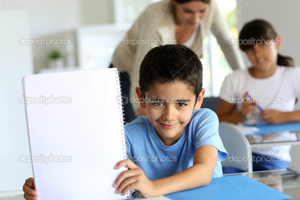 Portrait of cute little boy showing notebook towards camera