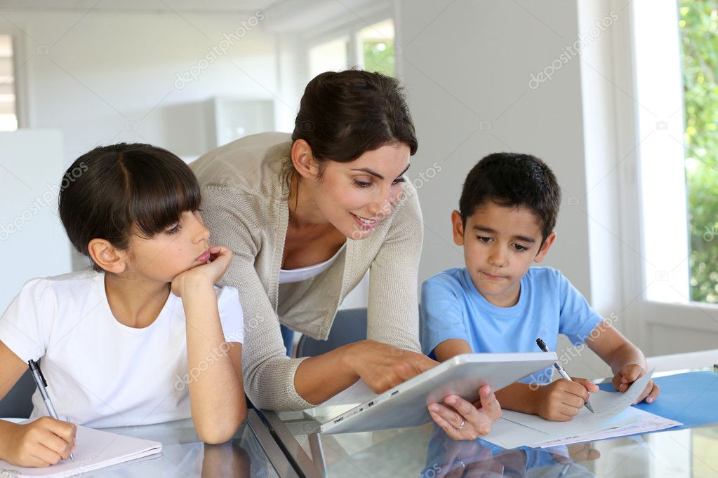 Woman teaching class to school children with digital tablet