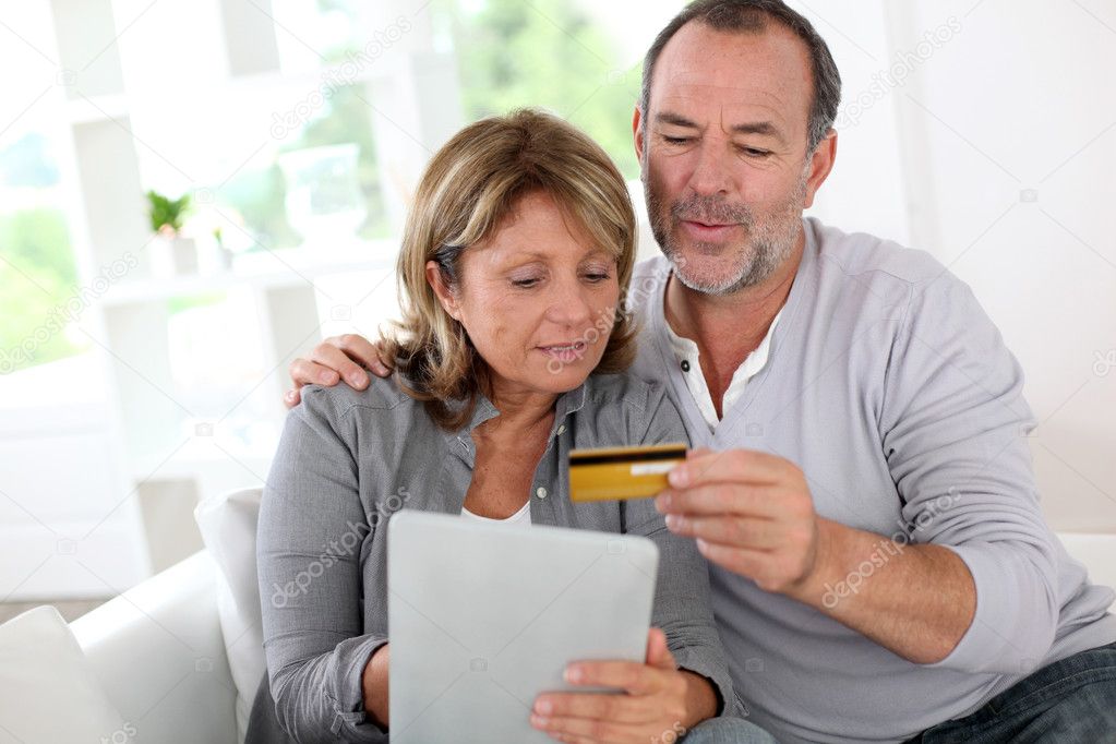 Senior couple using credit card to shop online
