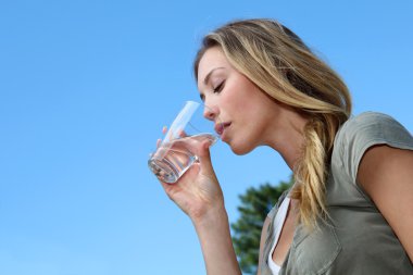 Closeup of blond woman drinking water from glass clipart