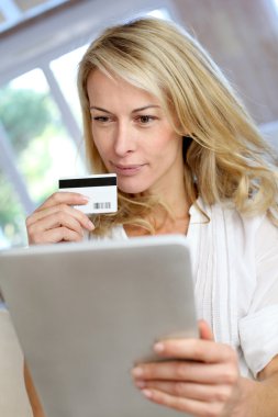 Sarışın, olgun bir kadın online alışveriş yapıyor.