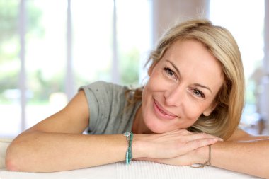 Beautiful blond mature woman relaxing in sofa clipart