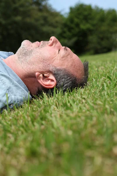 Closeup starší muž spící v trávě — Stock fotografie