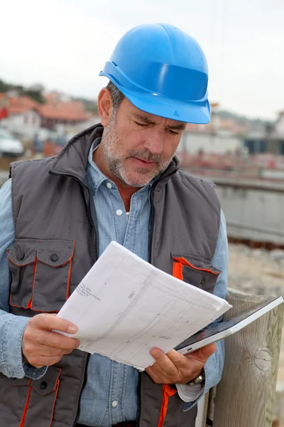 Direttore di costruzione che controlla il cantiere con il piano — Foto Stock