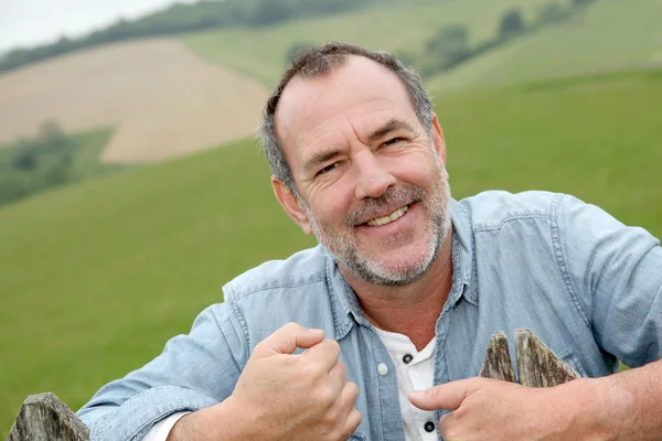 Retrato de agricultor sorridente inclinado na cerca — Fotografia de Stock