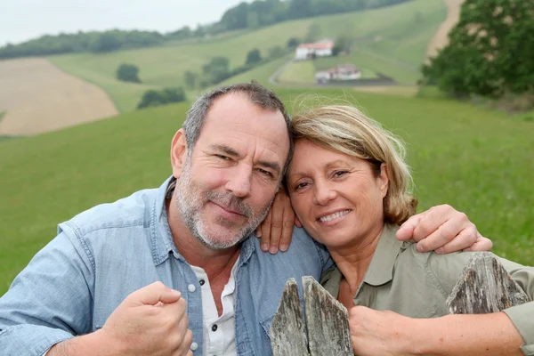 Casal sênior se apoiando em cerca no campo — Fotografia de Stock