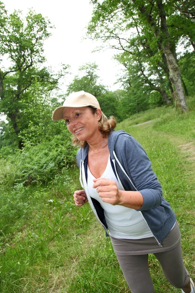 Senior woman jogging in forest — Stock Photo, Image