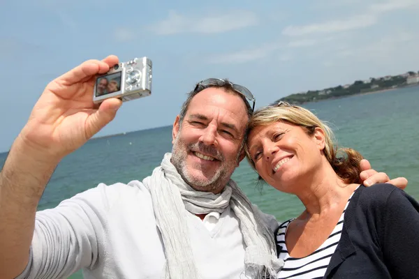 Retired couple taking picture of themselves by the sea — Stock Photo, Image