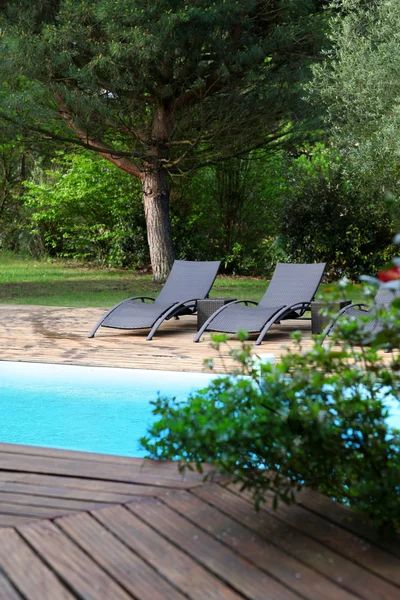 Closeup on long chairs set by private pool — Stock Photo, Image