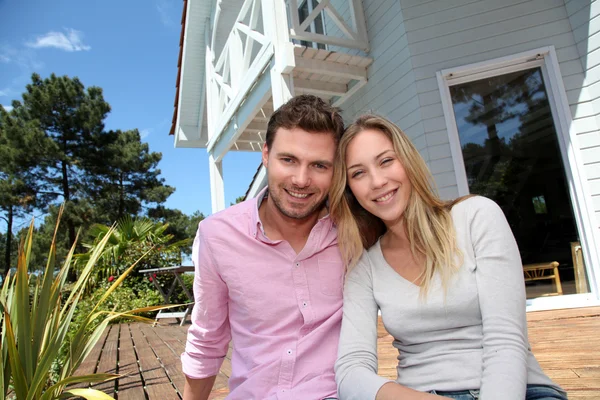 Retrato de pareja sonriente de pie frente a la casa —  Fotos de Stock