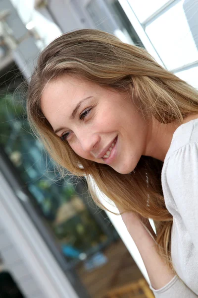 Portrait of beautiful blond woman leaning against home wall — Stock Photo, Image