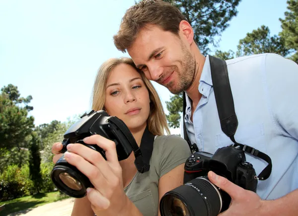 Casal olhando para fotos através da tela da câmera — Fotografia de Stock