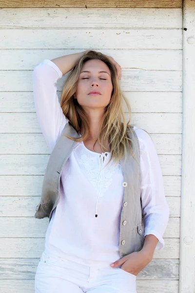 Blond woman leaning on wooden wall — Stock Photo, Image