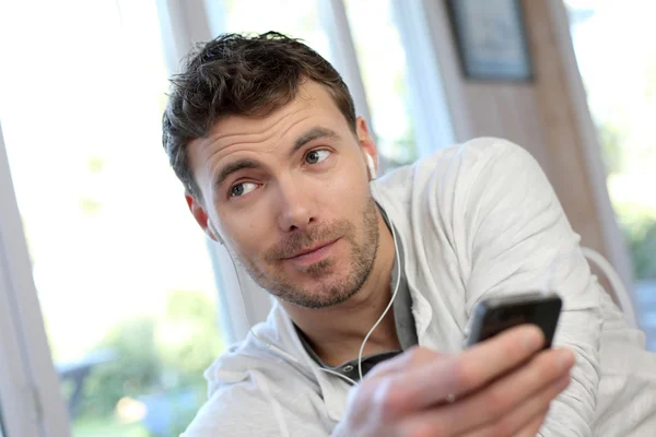 Young man using mobile phone with handsfree headset — Stock Photo, Image