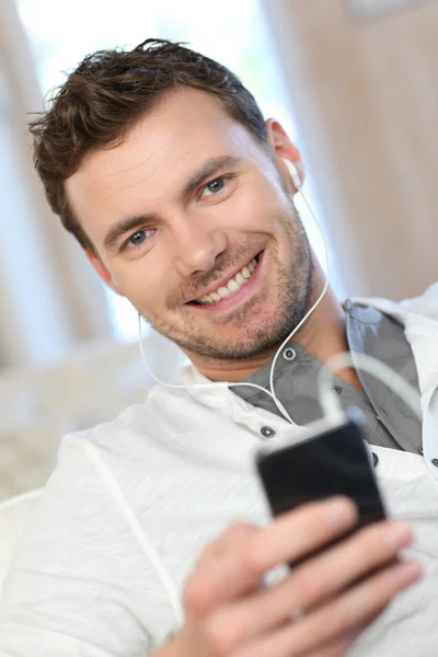 Glimlachende man met mobiele telefoon thuis — Stockfoto