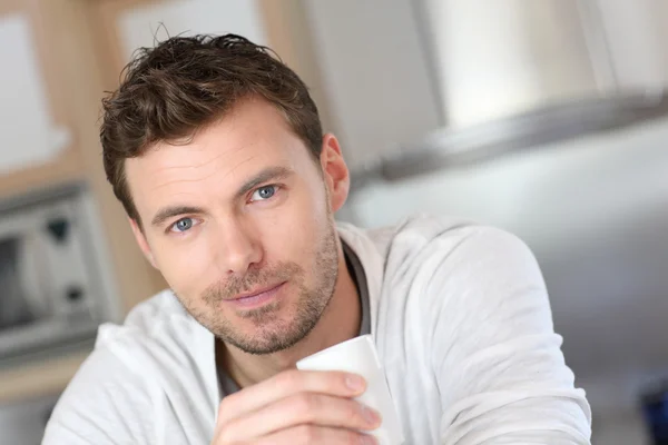 Portrait of handsome guy drinking coffee in home kitchen — Stock Photo, Image