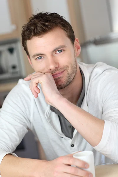 Portret van knappe jongen drinken koffie in huis keuken — Stockfoto