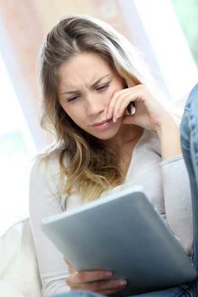 Jonge vrouw op zoek naar elektronische tablet met verbaasde blik — Stockfoto