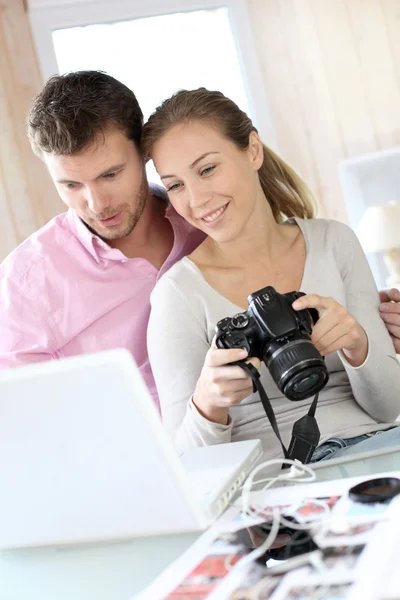 Casal em casa olhando para fotos na câmera e laptop — Fotografia de Stock