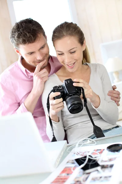 Casal em casa olhando para fotos na câmera e laptop — Fotografia de Stock