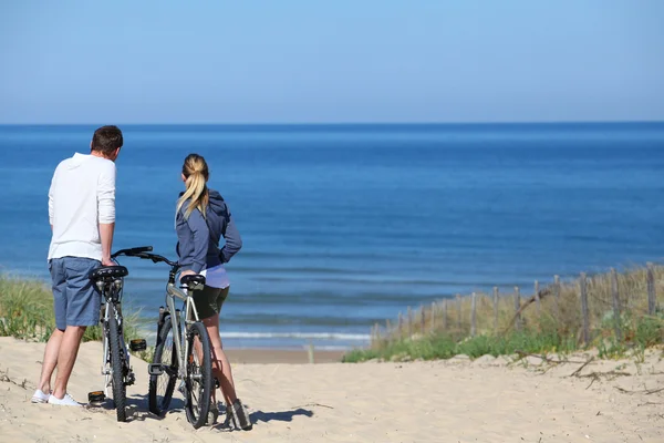 Paar mit Fahrrädern blickt auf das Meer — Stockfoto