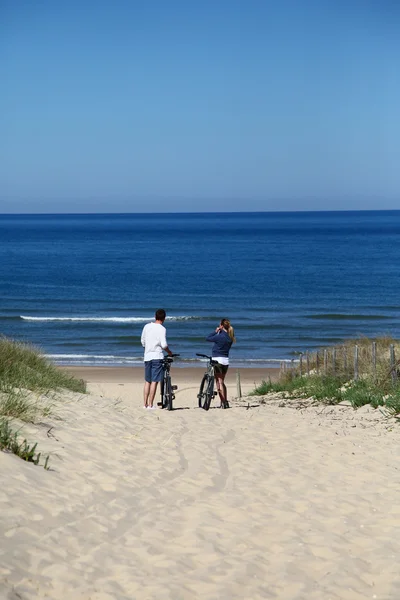 Ζευγάρι με τα ποδήλατα που κοιτάζοντας στον ωκεανό — Φωτογραφία Αρχείου