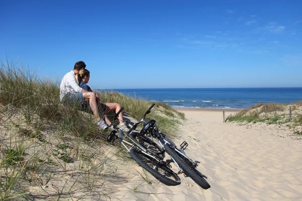 Couple sitting by bicycles on a sand dune — Stock Photo, Image