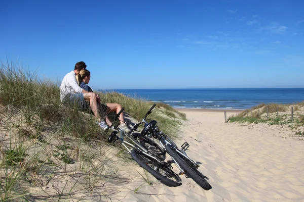 Pareja sentada en bicicleta en una duna de arena — Foto de Stock