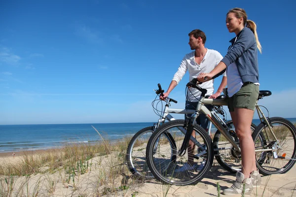 Couple with bicycles looking at the ocean — Stock Photo, Image