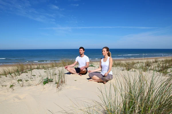 Yoga exercices kumlu bir plaj üzerinde yaparken çift — Stok fotoğraf