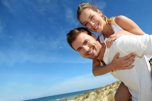 Man geven piggyback rit naar vriendin op een zand-duin — Stockfoto