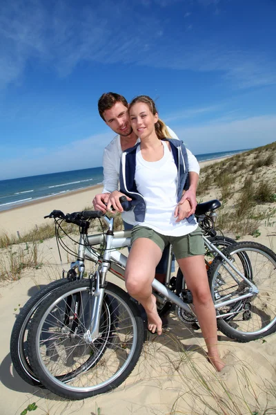 Alegre casal de bicicleta em uma duna de areia — Fotografia de Stock