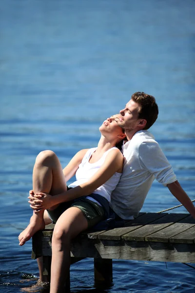 คู่รักพักผ่อนบนสะพานทะเลสาบในฤดูร้อน — ภาพถ่ายสต็อก