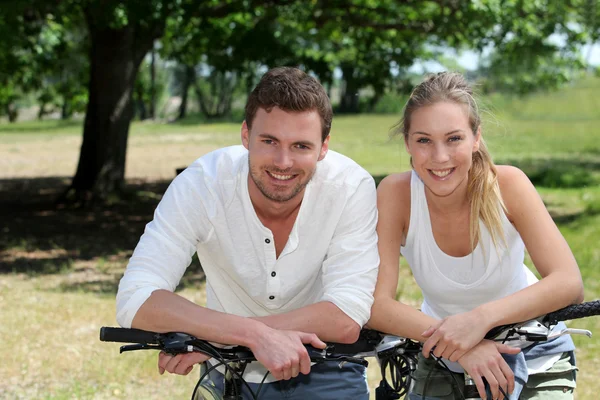 Portrait of cheerful couple riding bicycle in countryside — Stock Photo, Image