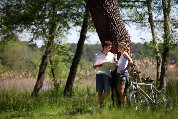 Couple sur une balade à vélo faire un arrêt pour regarder la carte — Photo