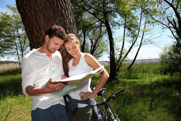 Couple on a bike ride making a stop to look at map — Stock Photo, Image