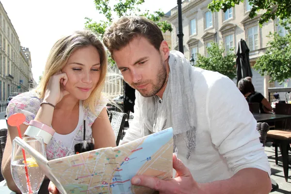 Couple assis sur une terrasse de café pour regarder la carte — Photo