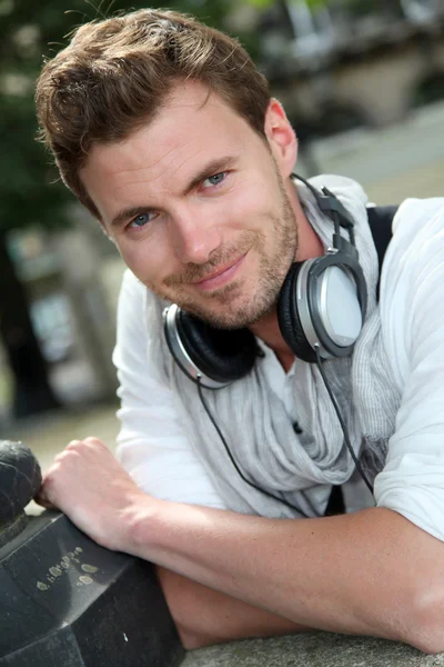 Portrait of guy with music headphones sitting in town — Stock Photo, Image