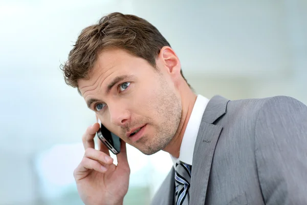 Empresario teniendo una llamada telefónica en el pasillo del edificio — Foto de Stock