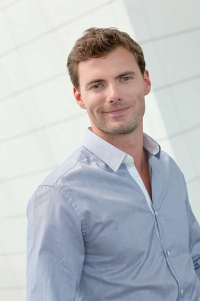 Smiling handsome guy standing in hallway — Stock Photo, Image