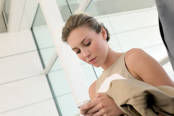 Actieve zakenvrouw in luchthaven met smartphone — Stockfoto
