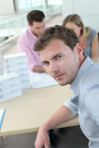 Portrait of man sitting in office with colleagues — Stock Photo, Image