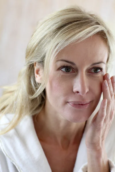 Attractive middle-aged woman applying comestics on her face — Stock Photo, Image